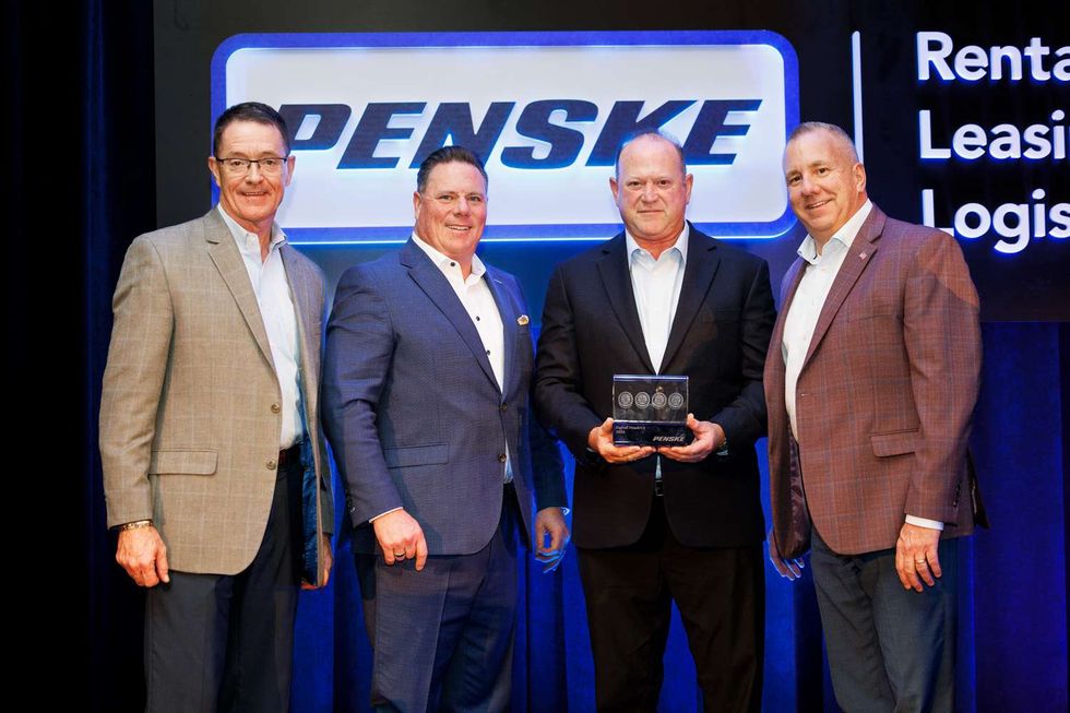 4 men posing with an award in front of the Penske logo