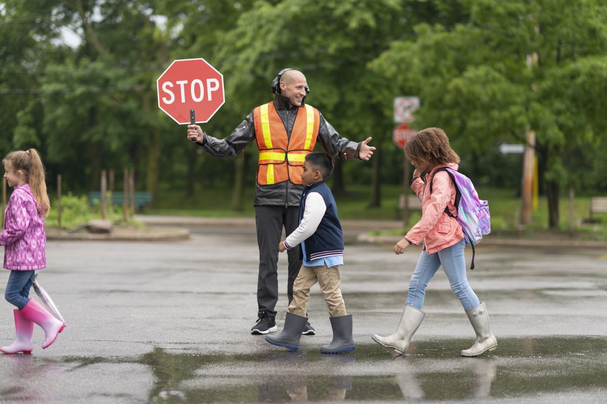 A crossing guard stops traffic as children cross the street
