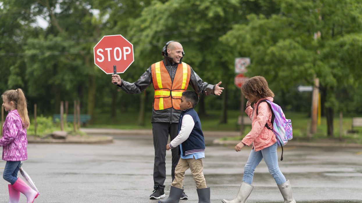 A crossing guard stops traffic as children cross the street