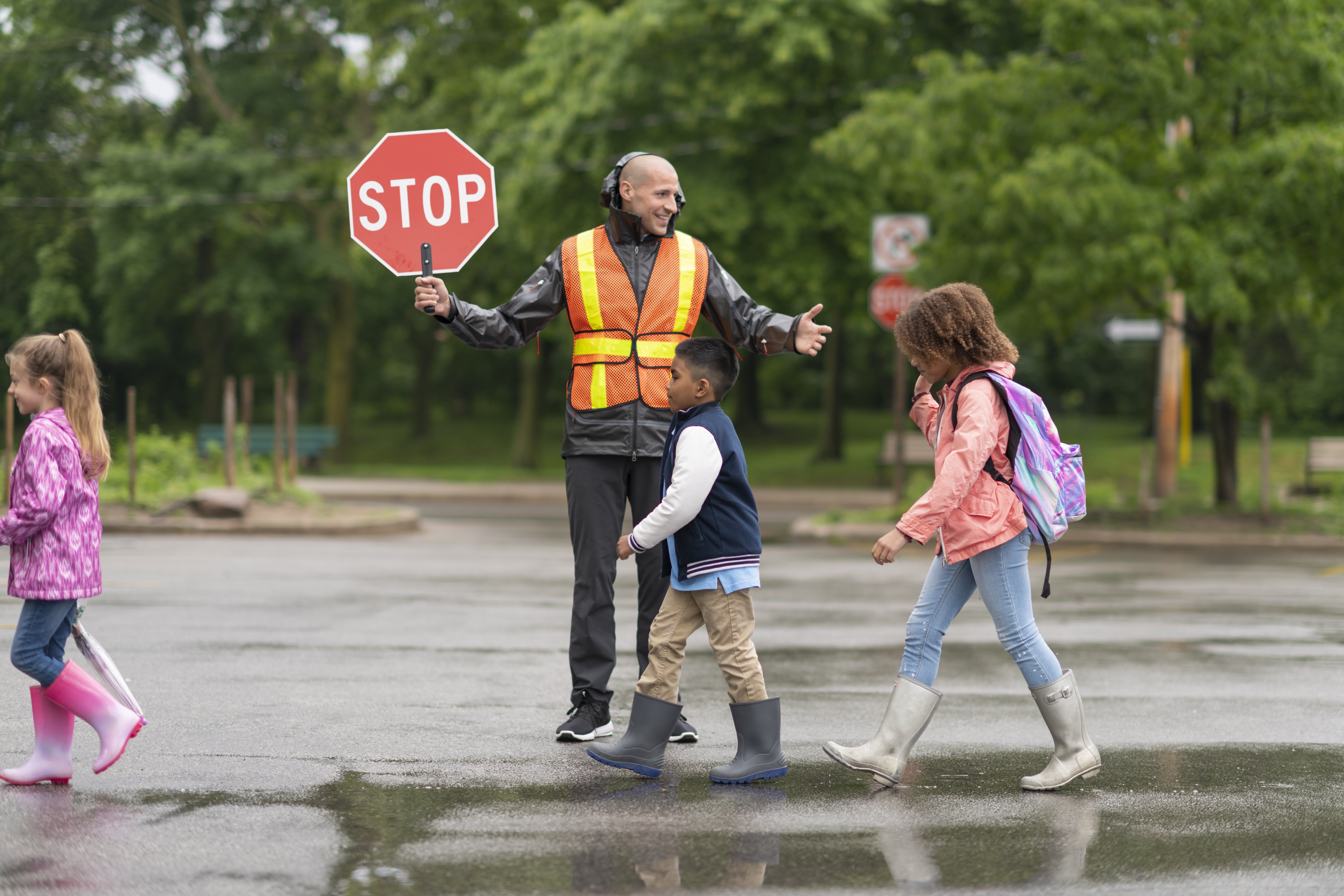 A crossing guard stops traffic as children cross the street