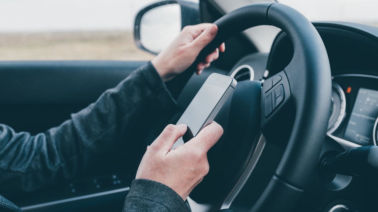 A driver takes their eyes off the road to look at their phone.