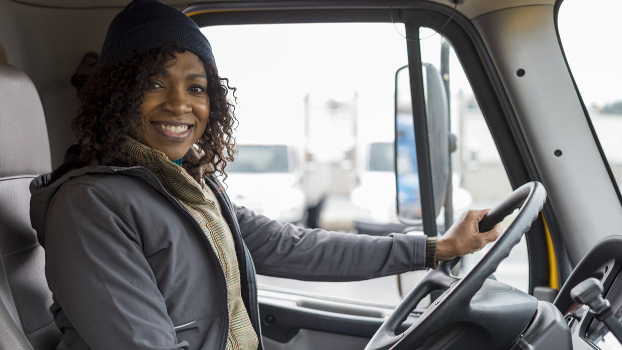A female driver smiles behind the wheel.