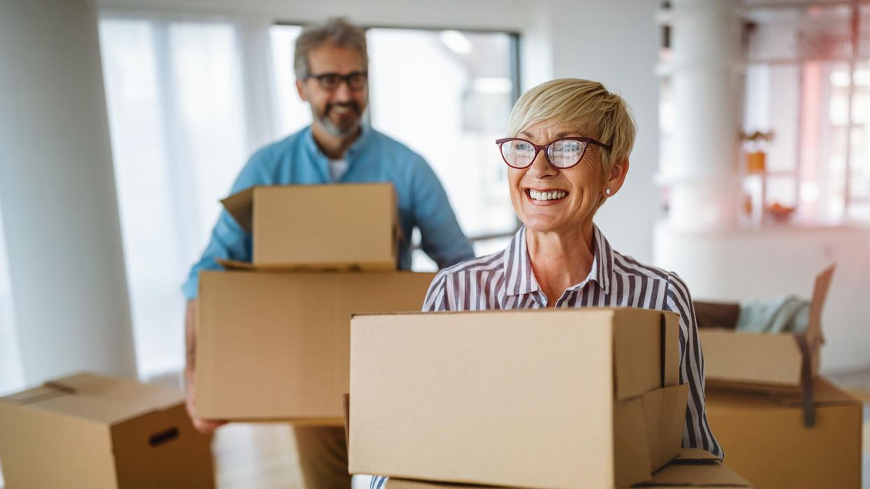 A happy senior couple holds moving boxes.