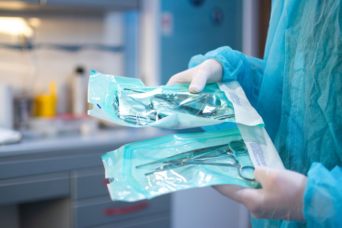A healthcare professional holds surgical kits.
