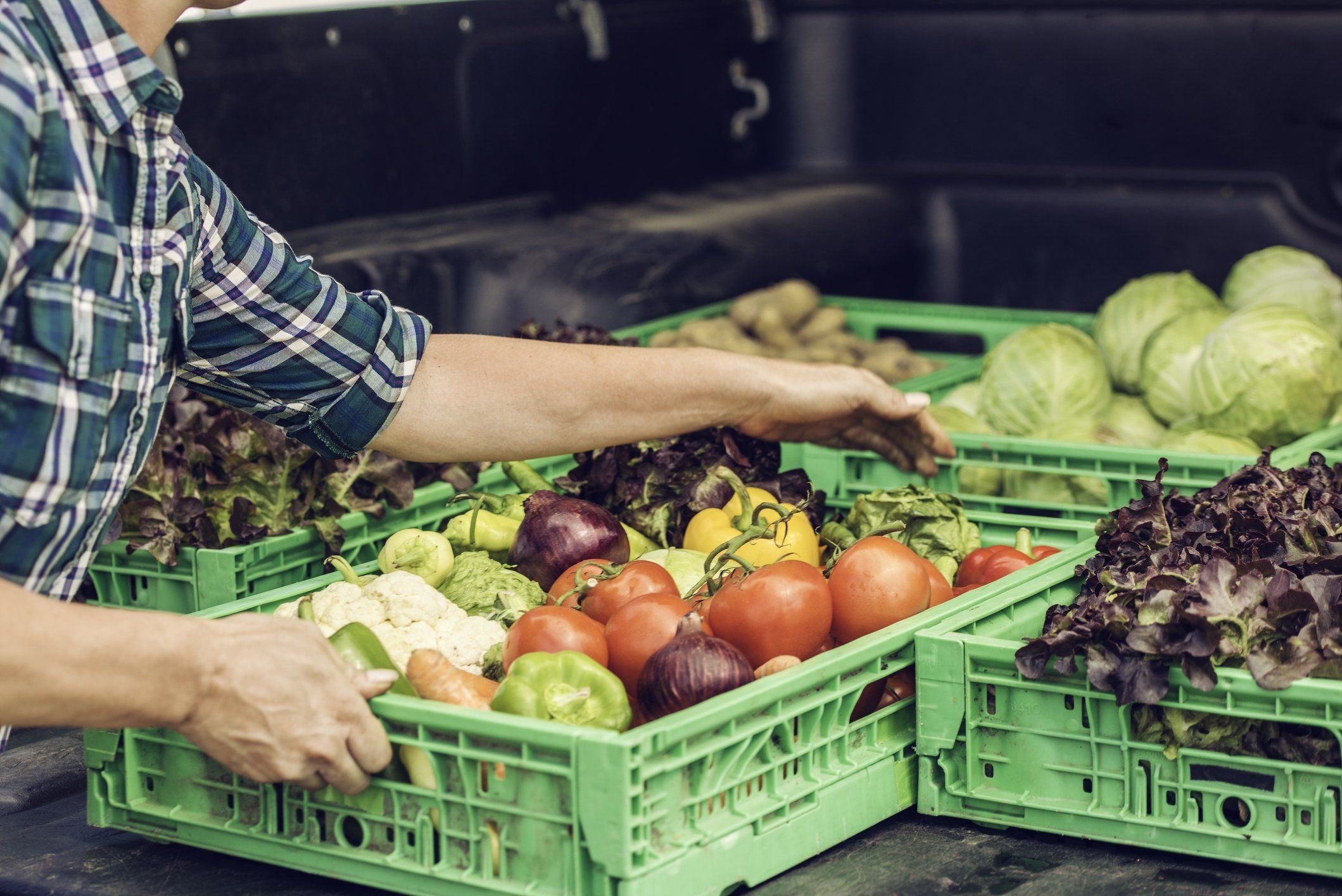 A man picks up a crate of fresh vegetables