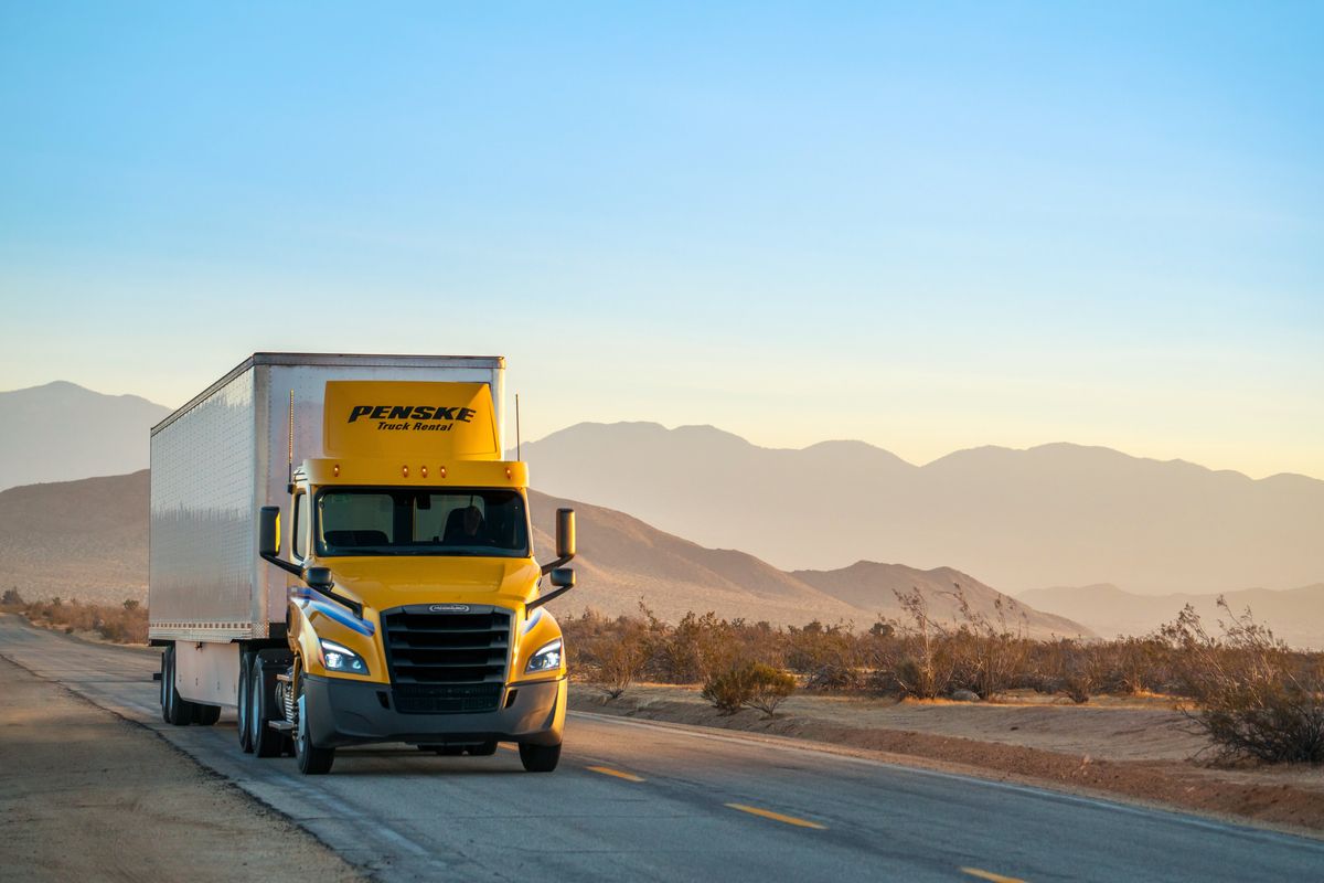 A Penske Tandem-Axle Day Cab drives on a high-desert road.