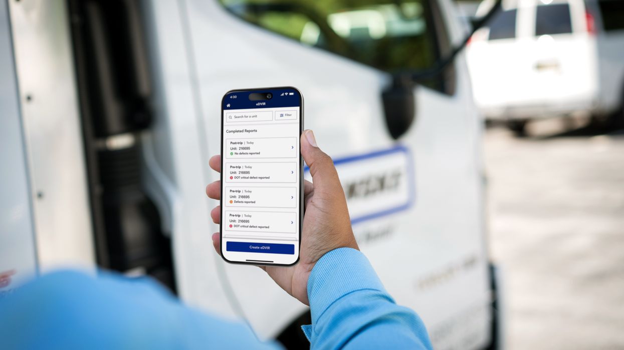 A person holds a smartphone displaying the Penske Driver mobile app's eDVIR feature.