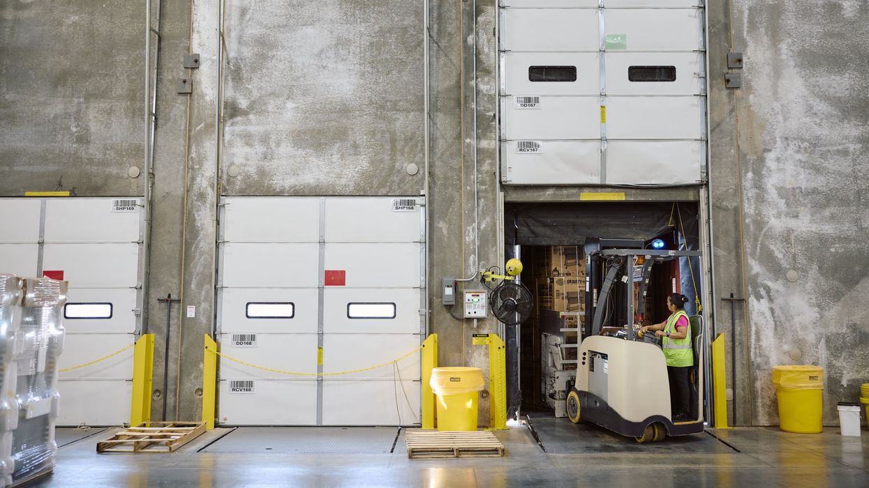 A retail warehouse worker uses a forklift to move boxes in a warehouse.