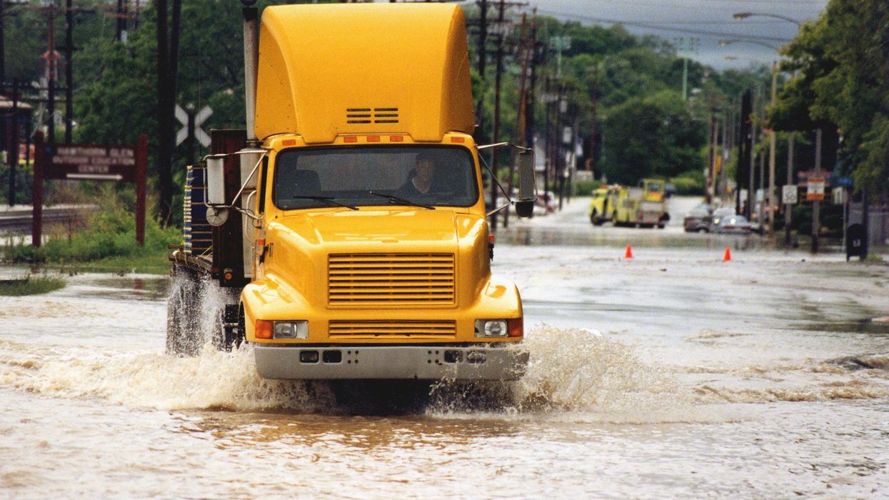 A semi-truck drivers through standing water