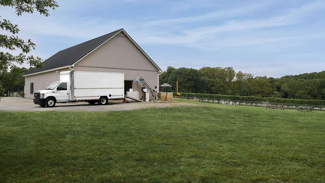A used white box truck sits in front of a building unloading cargo.