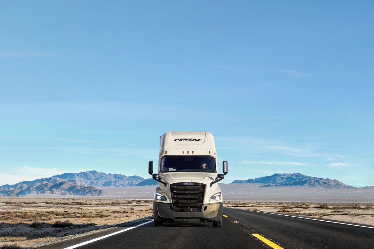 A white Penske truck on the road