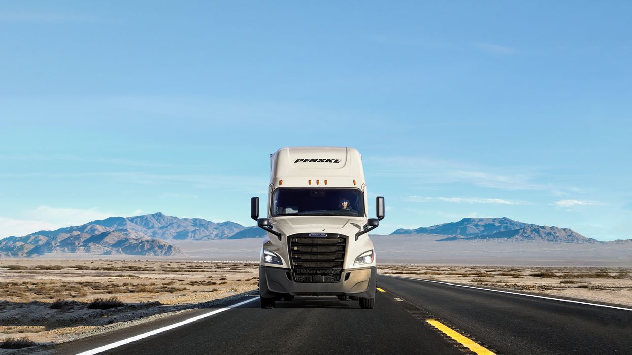 A white Penske truck on the road