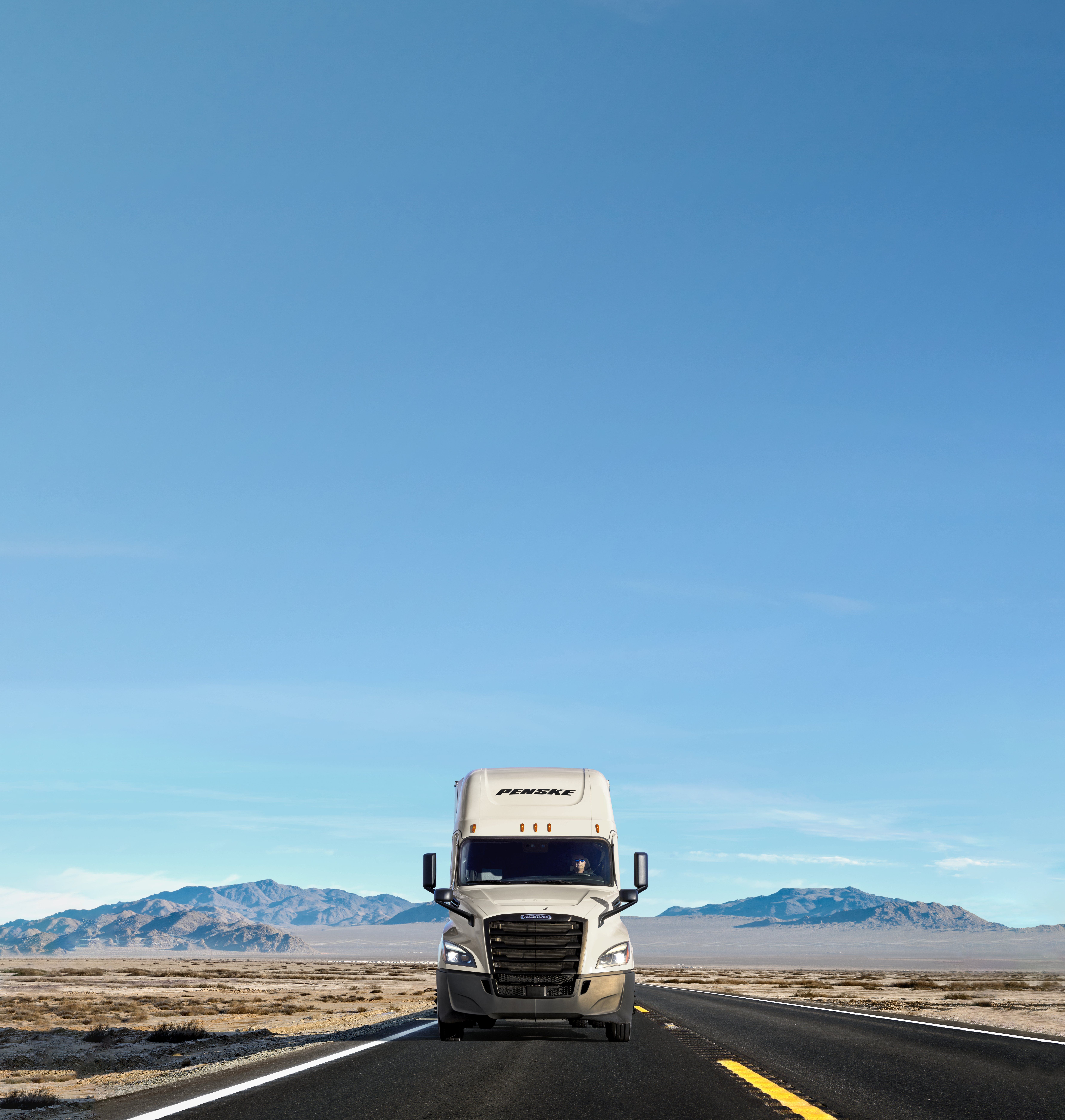 A white Penske truck on the road