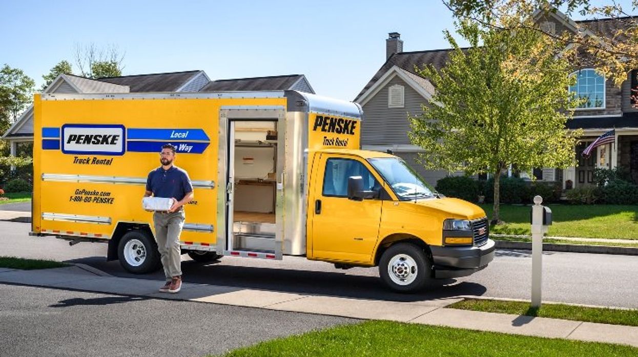 A yellow Penske box truck with shelves and curbside door.