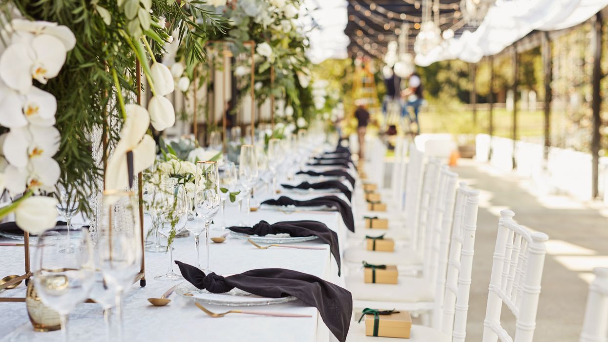 An event tablescape with black napkins and white flowers, chairs and tablecloth