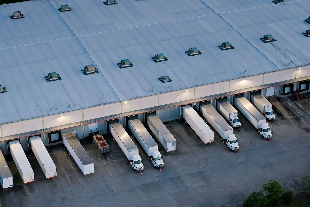 An overview shot of semi trucks and trailers parked at a warehouse.