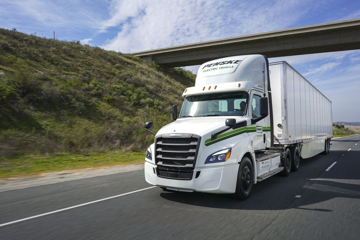 Electric tractor-trailer driving under a bridge.