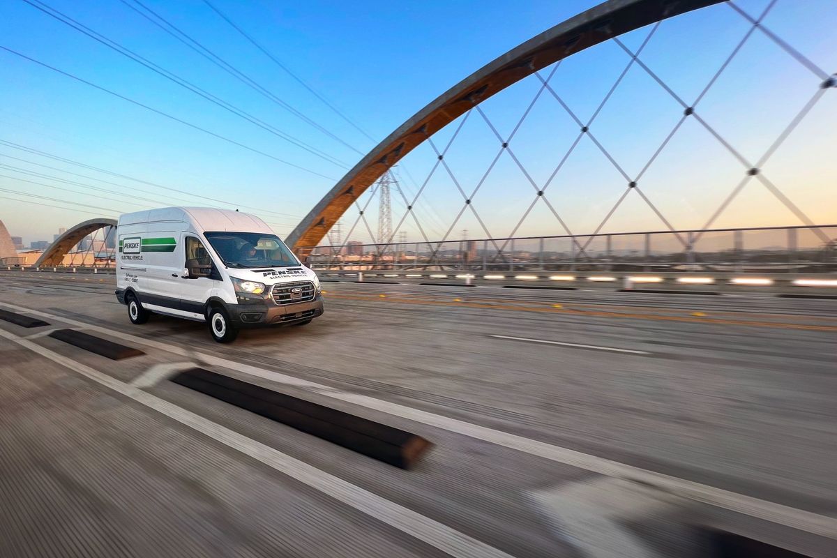 Electric transit van driving across a bridge.