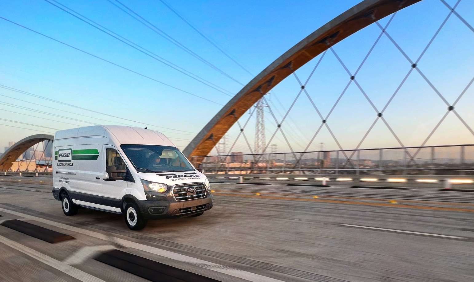 Electric transit van driving across a bridge.