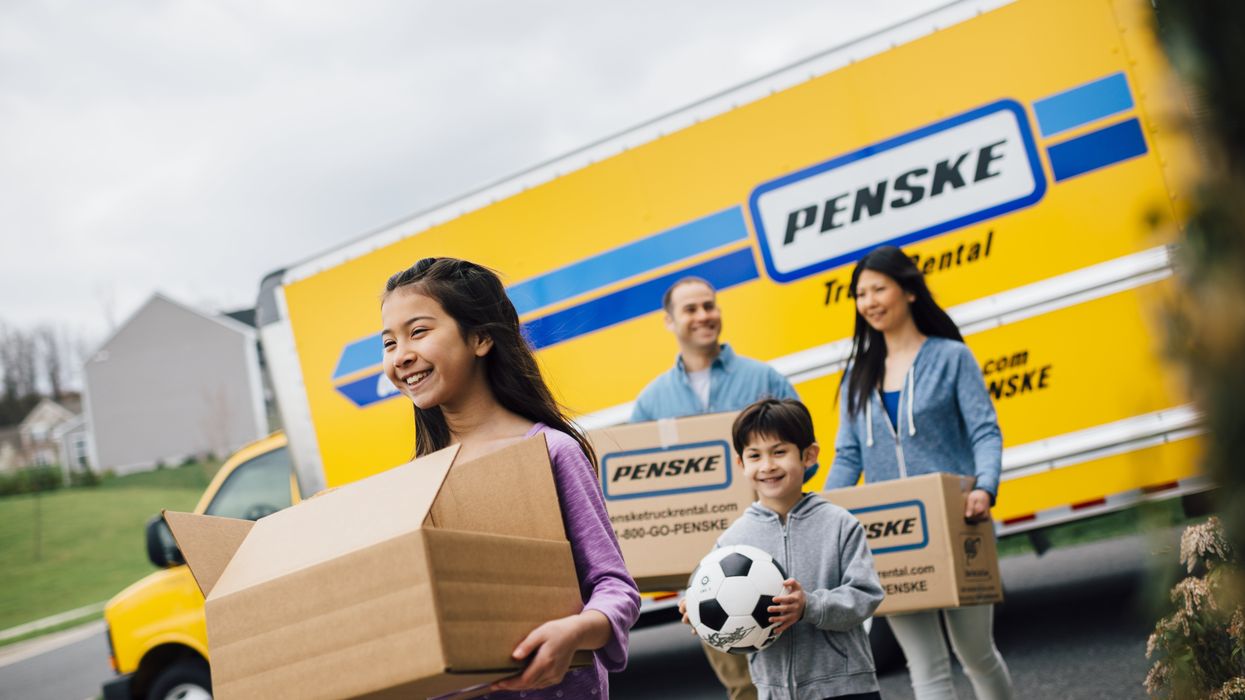 Family walking away from a moving truck carrying boxes.