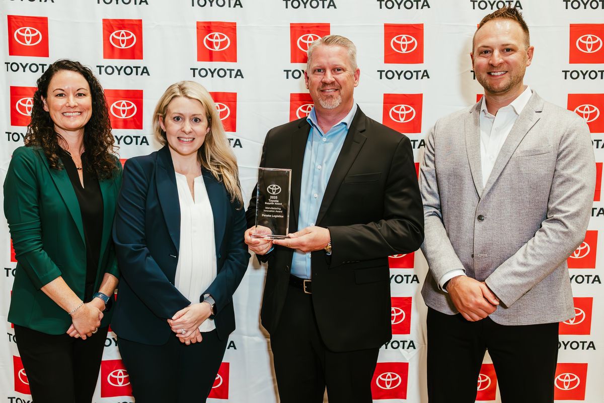 Four people standing in from of a Toyota backdrop holding an award.