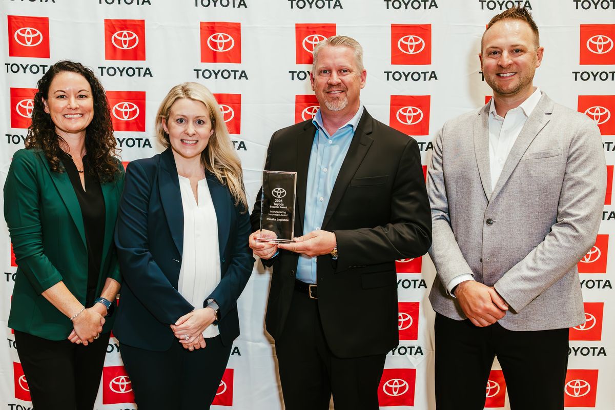 Four people standing in from of a Toyota backdrop holding an award.