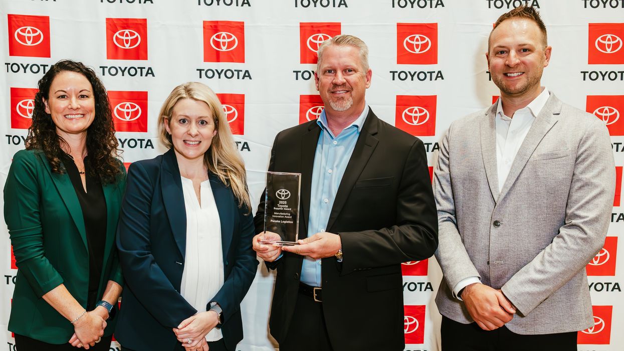 Four people standing in from of a Toyota backdrop holding an award.