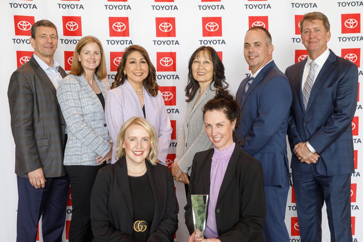 Group of people posing for a photo in front of a Toyota screen.