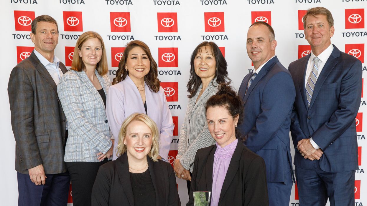 Group of people posing for a photo in front of a Toyota screen.
