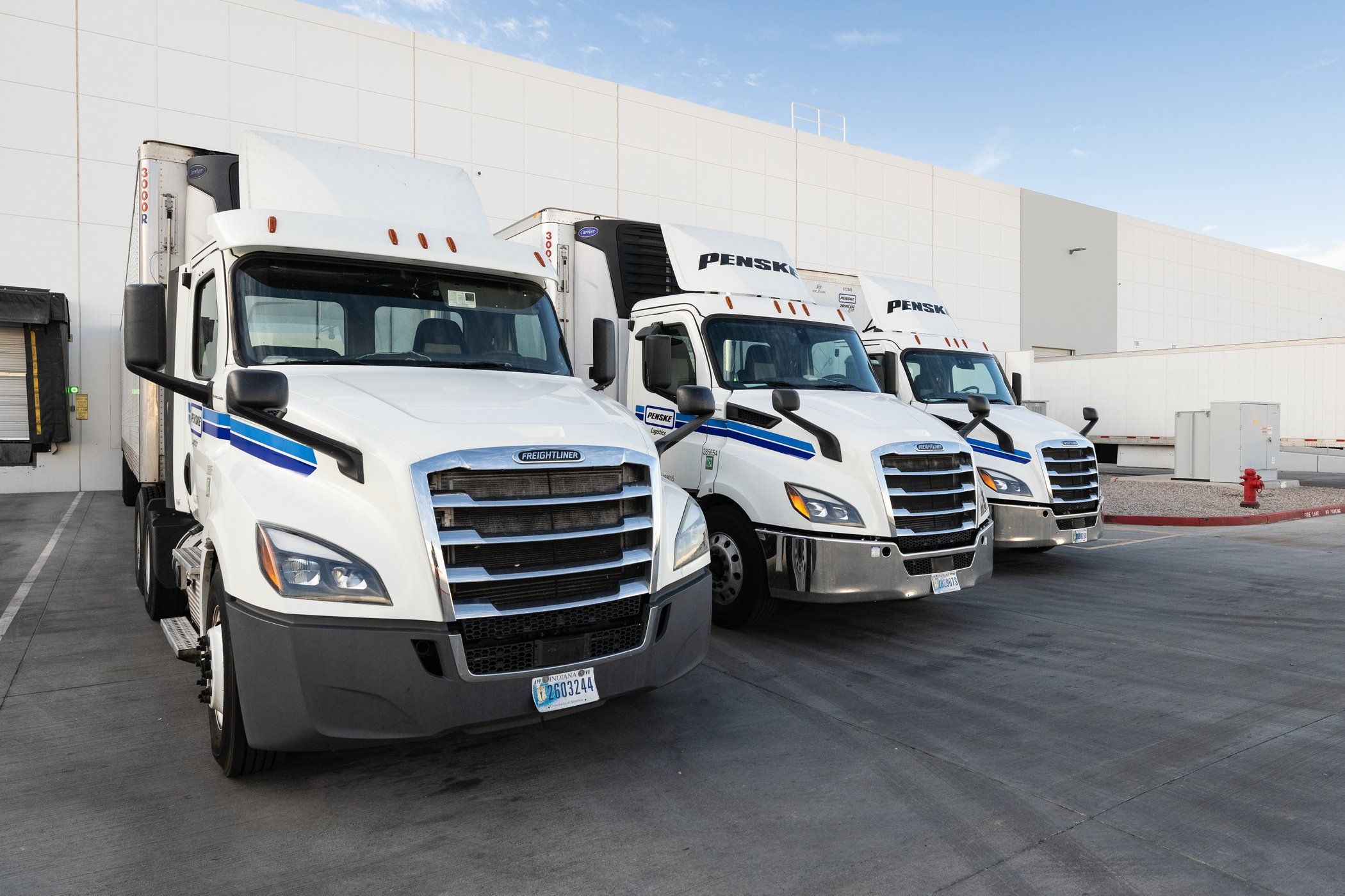 Penske tractor trailers backed up to a loading dock.