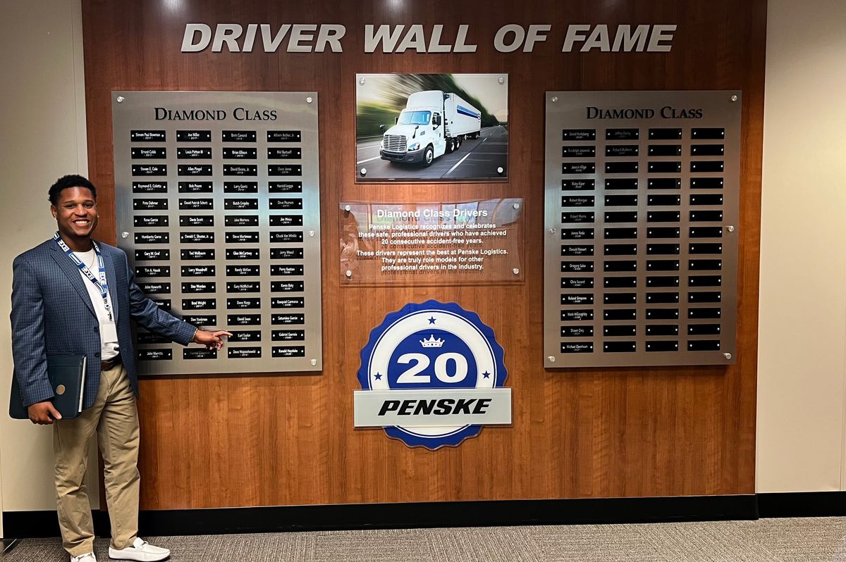 Man pointing to his name on a "Driver Wall of Fame."