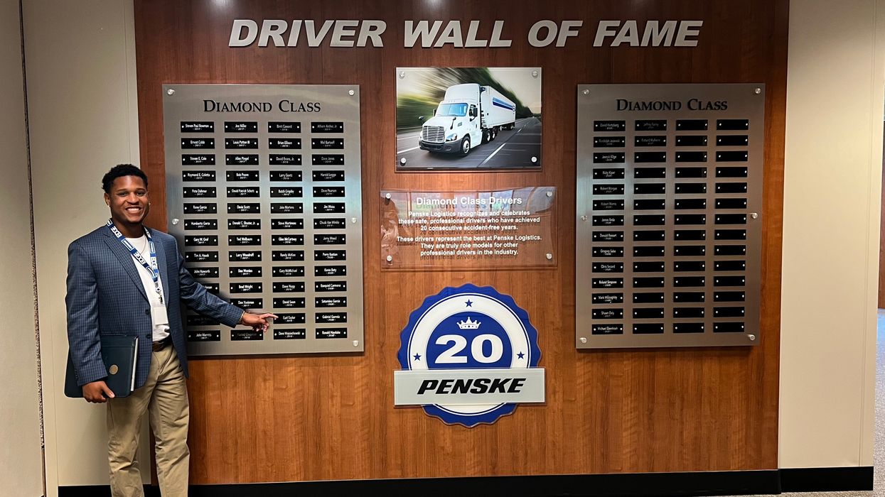 Man pointing to his name on a "Driver Wall of Fame."