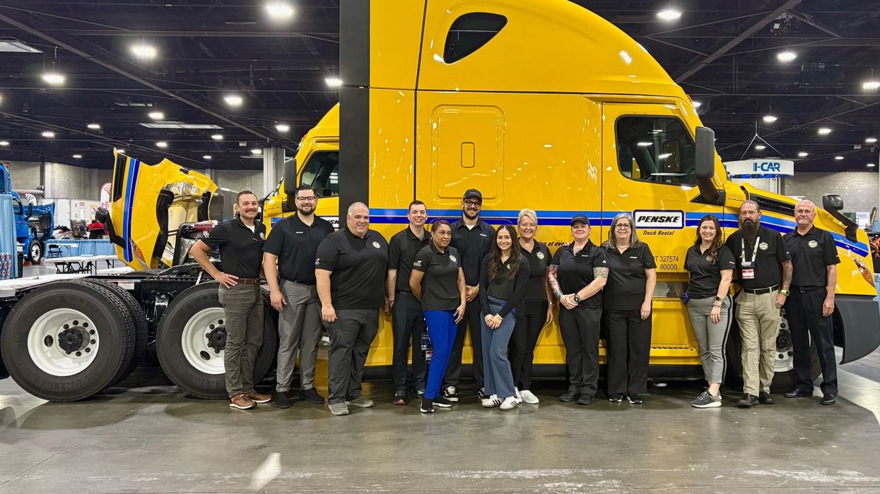 Penske employees lined up in front of a yellow Penske truck