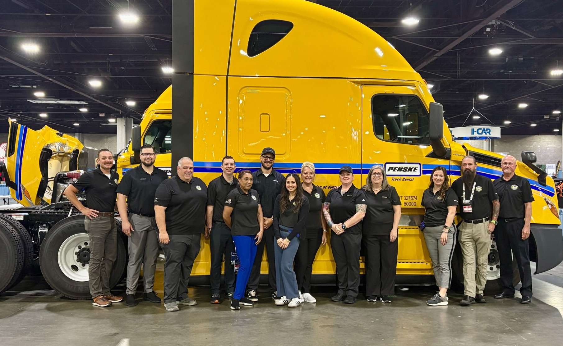 Penske employees lined up in front of a yellow Penske truck