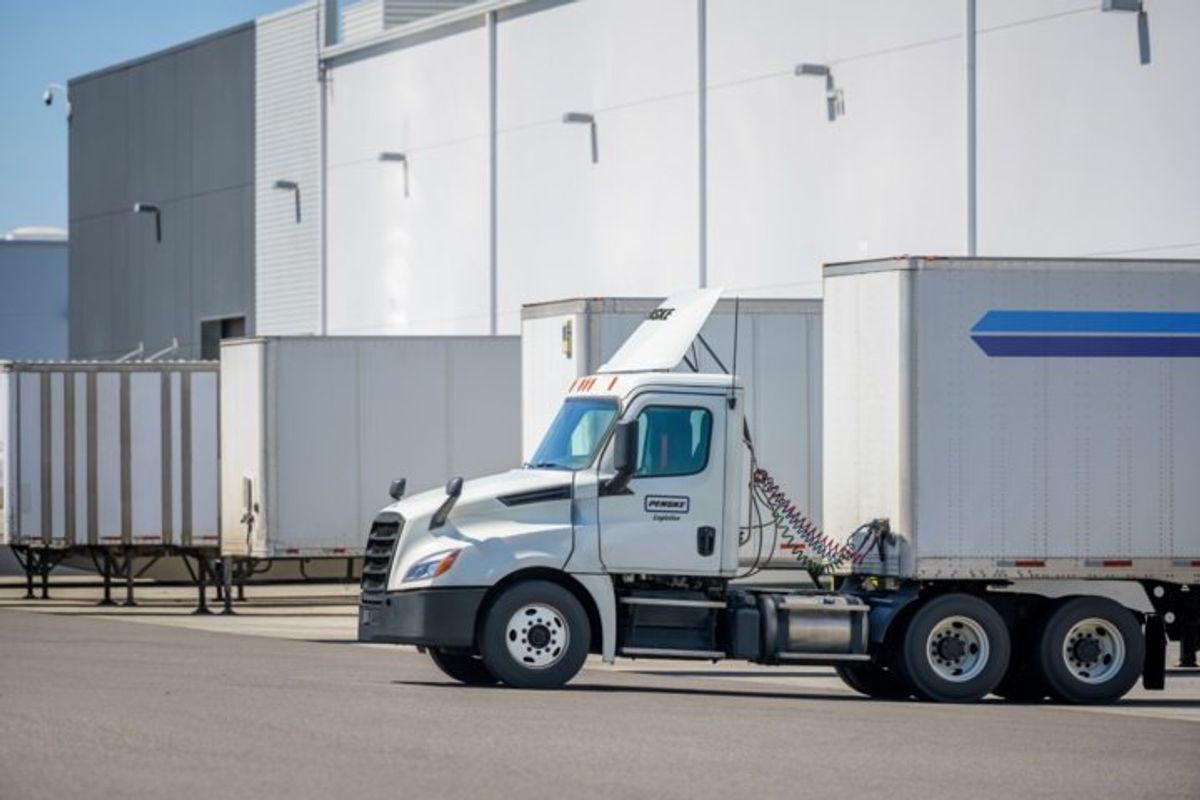 Penske Logistics trucks parked at the loading dock of a warehouse