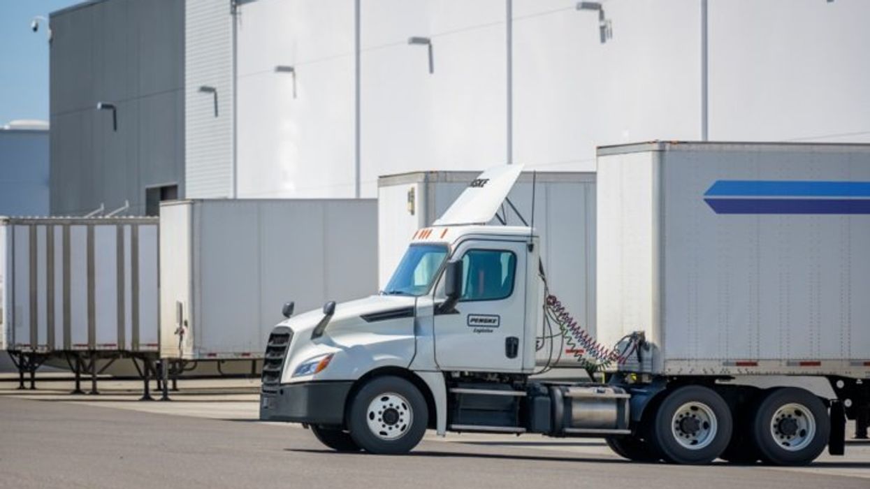 Penske Logistics trucks parked at the loading dock of a warehouse