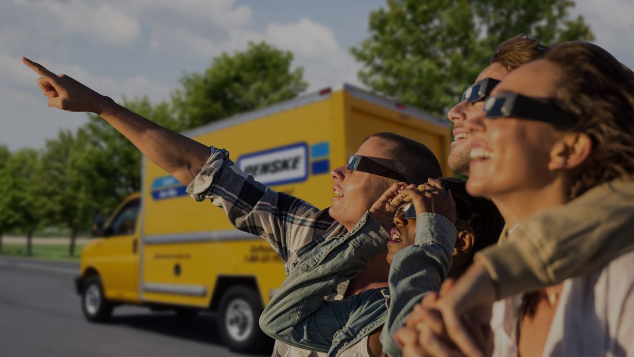 People wearing eclipse glasses and pointing toward the eclipse.