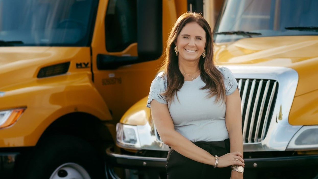 Photo of woman standing in front of yellow trucks