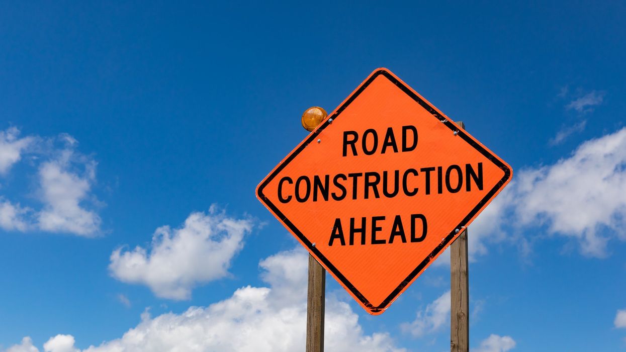 Road construction ahead sign against a clear sky.