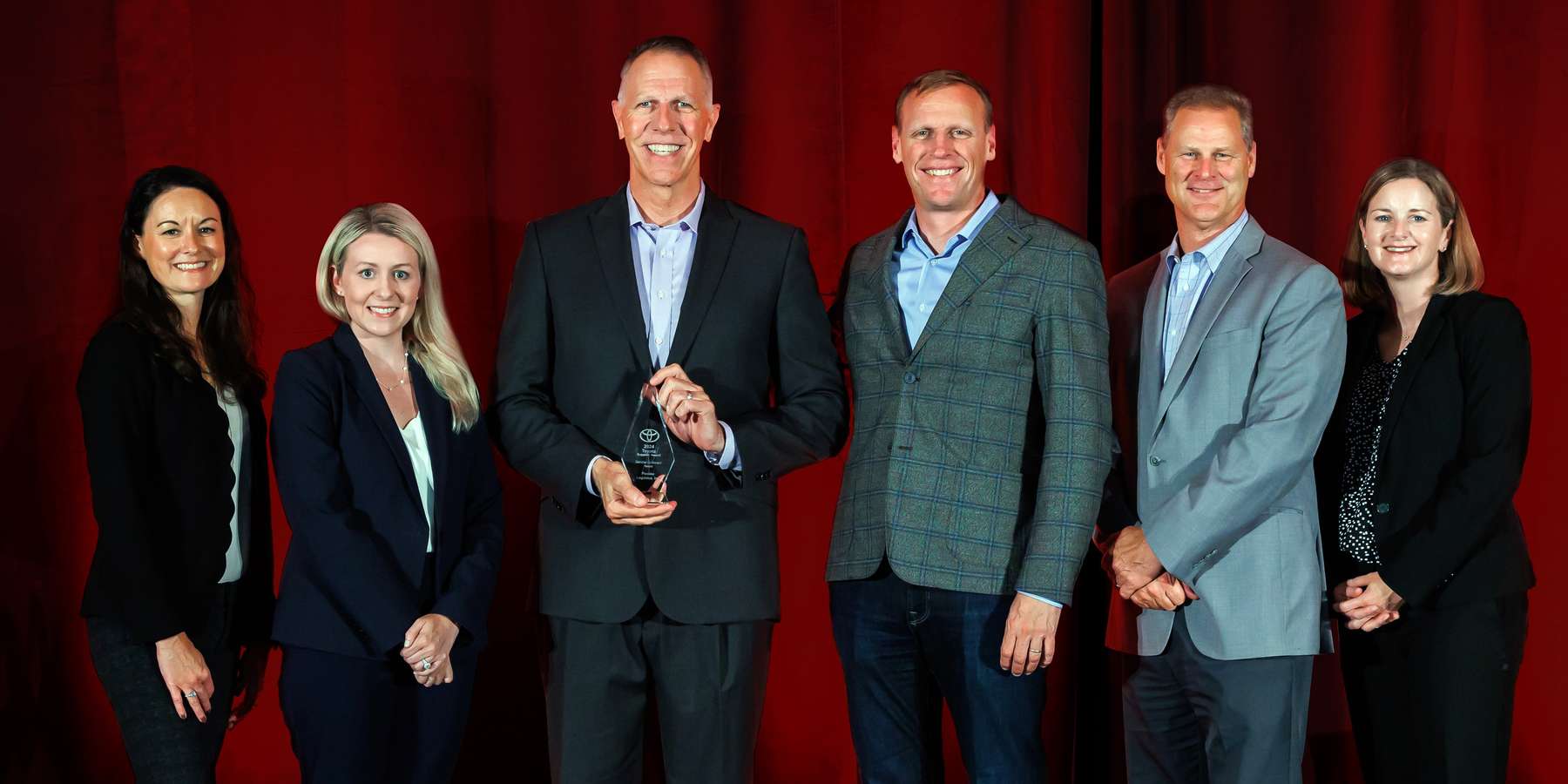Six people from Penske Logistics posing with an award from Toyota North America