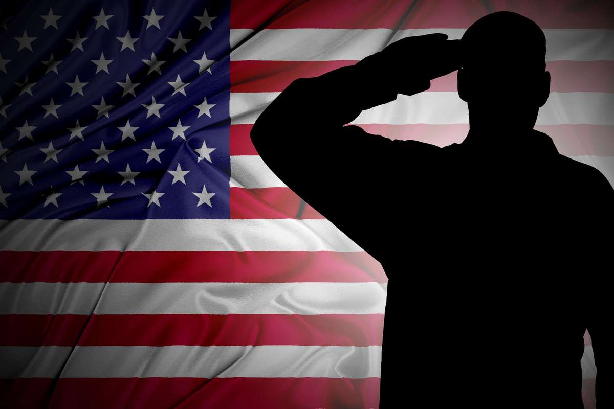 Soldier's saluting silhouette against an American flag