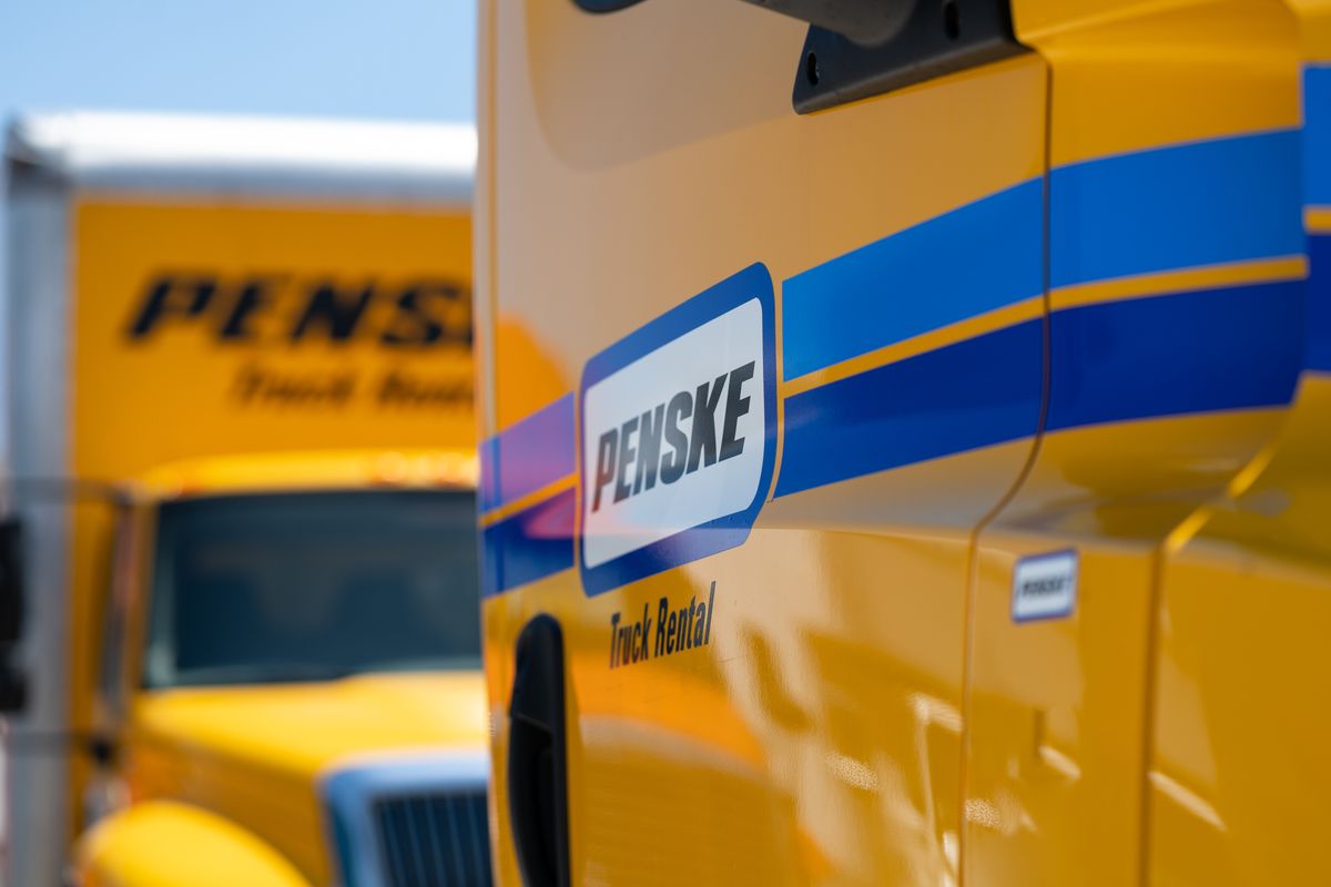 The Penske logo on the side of a yellow Penske truck.