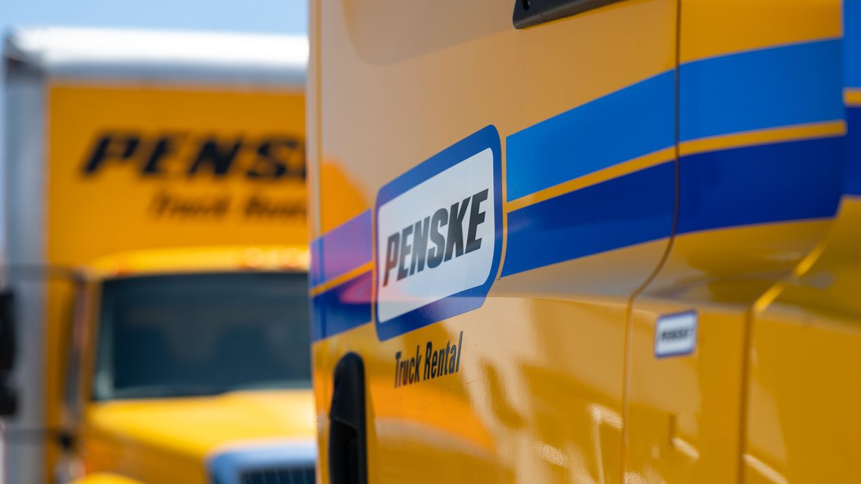 The Penske logo on the side of a yellow Penske truck.