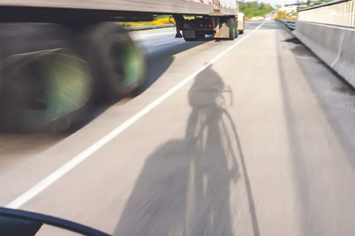 Truck driving next to a bicyclist. 