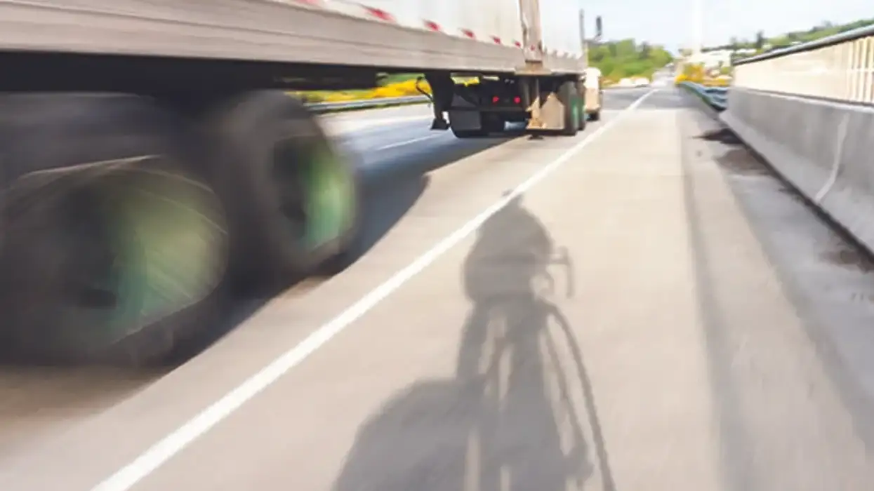 Truck driving next to a bicyclist.