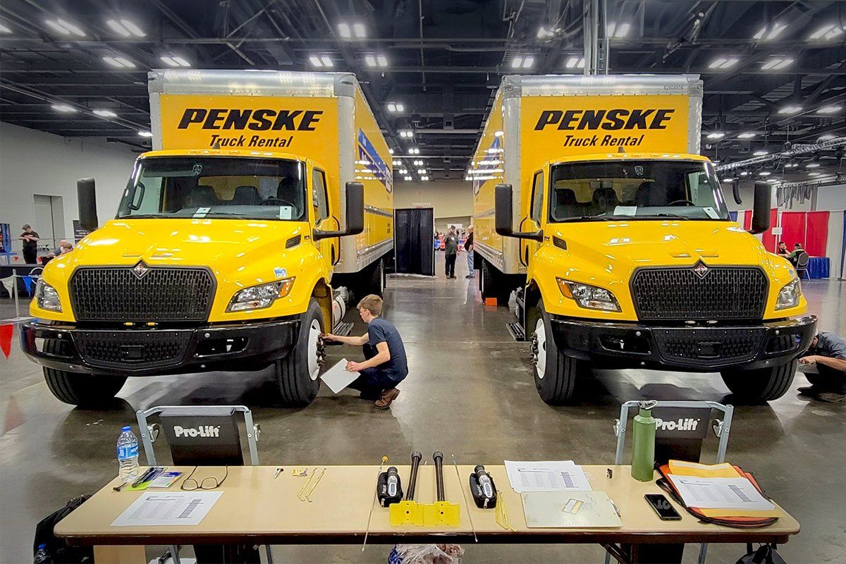 Two box trucks set up on a show floor to be inspected by aspiring technicians.