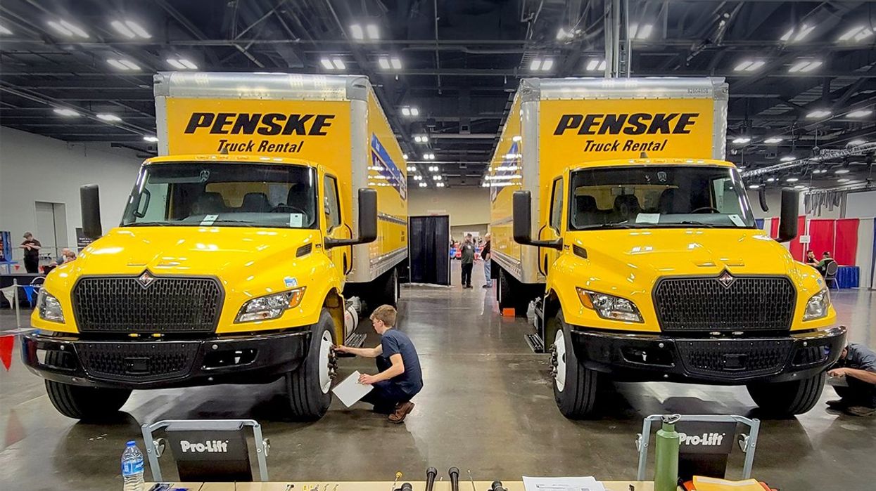 Two box trucks set up on a show floor to be inspected by aspiring technicians.