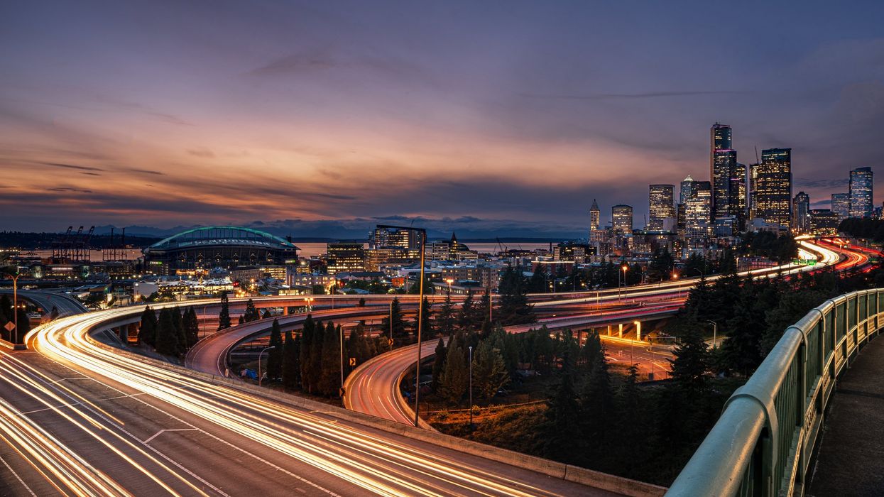 Vehicles speeding down a freeway outside a city at night