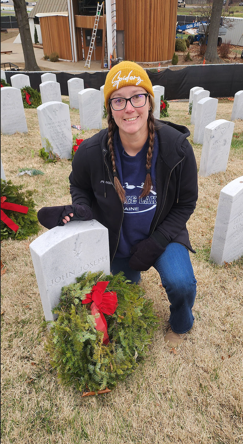 Woman kneeling near a gravestone.