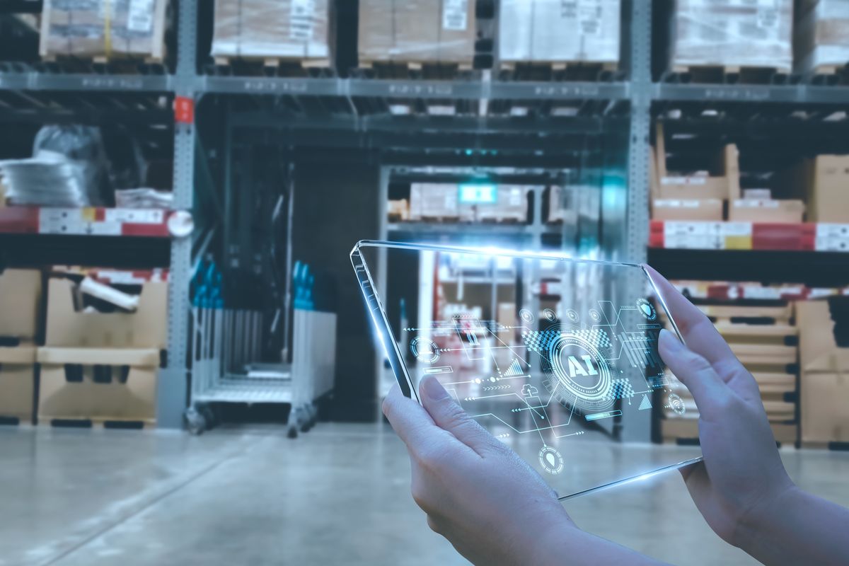 Woman's hands holding clear device with the letters "AI" on it in a warehouse